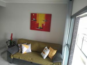 瓜鲁雅Apartamento Guarujá Astúrias的客厅的沙发,墙上有绘画作品
