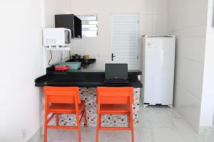 伯迪亚哥Kitnet Maitinga的厨房配有两把橙色椅子和台面上的笔记本电脑