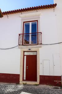 莱里亚Canto dos Poetas的白色的建筑,设有红色的门和阳台