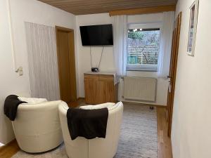 巴特恩多夫Ferienwohnungen Gmeiner的客厅配有两把白色椅子和电视