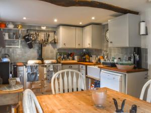 Holmbury Saint MaryChapel Cottage,的厨房配有白色橱柜和木桌