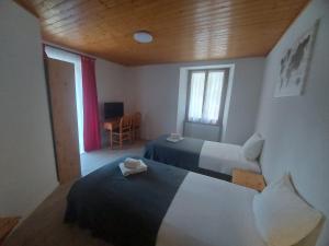 Le ChatelardLES TOURISTES的客房设有两张床、一张桌子和一扇窗户。