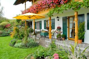 罗滕布Ferienwohnung Freißl的一座房子,设有一座带遮阳伞和鲜花的庭院