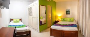 皮乌拉Hotel Country Boutique的一间卧室设有两张带绿色墙壁的床和一张桌子