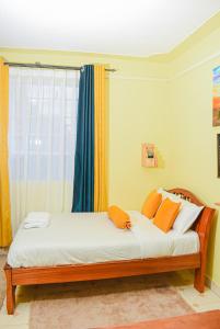 奈瓦沙Naivasha Southlake apartments的窗户间里一张带橙色枕头的床