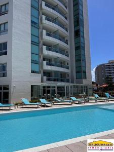 埃斯特角城Apartamento Punta del Este,Wind Tower 2 dormitorios的一座带躺椅的游泳池和一座建筑