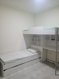 蒙加瓜Bela Mar Mongaguá的白色的客房配有双层床和书桌。