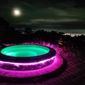 卡利Romero Glamping y Cabañas的夜晚,紫色和绿色的喷泉与月亮相映