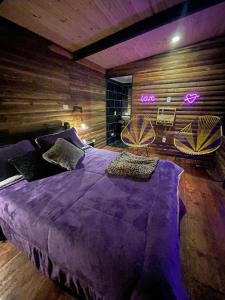 卡利Romero Glamping y Cabañas的一间卧室配有一张大紫色床和两把椅子