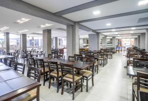 弗洛里亚诺波利斯Boulevard Beach Canasvieiras Hotel的餐厅设有木桌、椅子和窗户。
