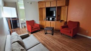 夏洛特Studios & Suites 4 Less Charlotte的客厅配有沙发、两把椅子和电视