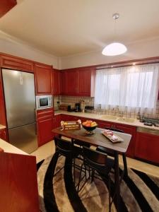 斯巴达Thira Apartment near Athens Airport的厨房配有红色橱柜、桌子和冰箱