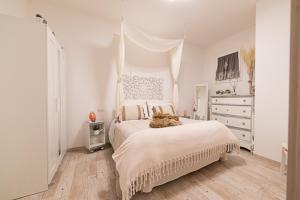法萨诺IL NIDO DEL FASO的一间白色的卧室,床上放着一只猫