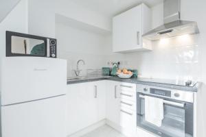 米尔顿凯恩斯Cosy Two bed Apartment for family and contractors Milton Keynes by O&J Real Estate的白色的厨房配有炉灶和微波炉。
