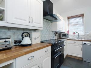 华顿Horseshoe House - Ukc2743的厨房配有白色橱柜和炉灶烤箱。