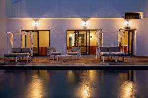 卡尔维Best Western Hotel Casa Bianca的一间设有椅子的房间,晚上设有游泳池