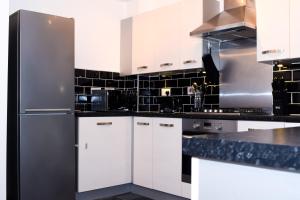 伍尔弗汉普顿Modern 3 Bed House的厨房配有白色橱柜和不锈钢冰箱