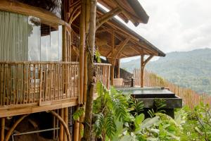 KlungkungDreamy Cliffside Bamboo Villa with Pool and View的木屋设有阳台,享有山脉的背景