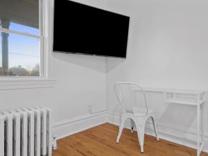 匹兹堡Bloomfield/Shadyside @E Stylish and Modern Private Bedroom with Shared Bathroom的白色客房的白色椅子和平面电视