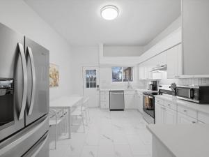 匹兹堡Bloomfield/Shadyside @E Stylish and Modern Private Bedroom with Shared Bathroom的白色的厨房配有桌子和冰箱