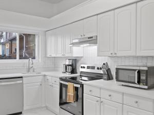 匹兹堡Bloomfield/Shadyside @E Stylish and Modern Private Bedroom with Shared Bathroom的厨房配有白色橱柜和炉灶烤箱。