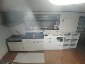 Kitsuki横城ゲストハウス的小厨房配有白色橱柜和水槽