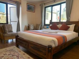 加德满都Hotel Ramanam的一间卧室设有一张大床、一把椅子和窗户。