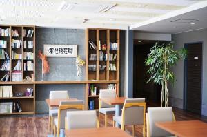 饭田市Silk Hotel的图书馆配有桌椅和书架