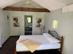 安东尼奥港Jamaica Colors Hotel and Eco-Retreat的一间卧室配有白色床单和一间浴室
