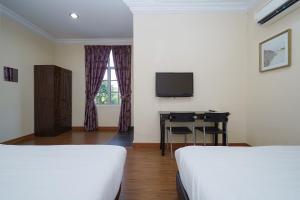 班吉Super OYO 90009 Bangi Sri Minang Guesthouse的客房设有两张床、一张桌子和一台电视。