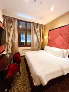 新加坡Nostalgia Hotel的酒店客房设有一张大床和一张书桌。