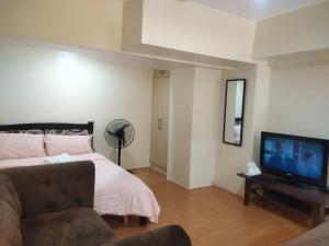 锡朗Monteluce Staycation的一间卧室配有一张床和一台平面电视