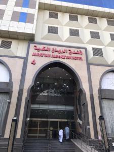 麦加Al Rayyan Towers 4的两个人走进建筑物,上面有标志