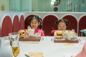 深圳深圳华侨城洲际大酒店的两个小女孩坐在桌子上吃汉堡