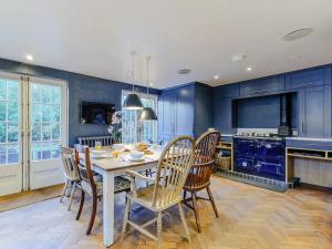 法弗舍姆Anchor Light Cottage的厨房配有蓝色橱柜和桌椅