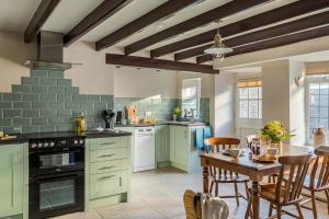 斯卡伯勒Garth Cottage in West Ayton的厨房配有绿色橱柜和桌椅