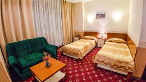 卡拉甘达Reikartz Dostar Karaganda的酒店客房,设有两张床和一张绿色沙发