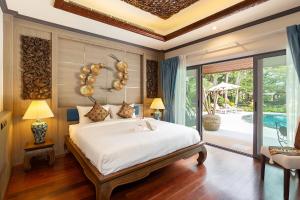 拉威海滩Villa Carlos, Luxury 7 BDR Private Pool Villa, Baan Bua Nai Harn, Phuket的一间带大床的卧室和一个游泳池