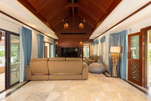 拉威海滩Villa Carlos, Luxury 7 BDR Private Pool Villa, Baan Bua Nai Harn, Phuket的带沙发和电视的客厅
