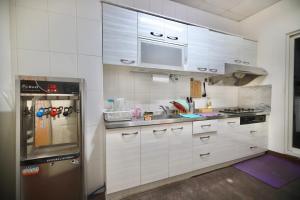 恒春古城好窩旅店的厨房配有白色橱柜和不锈钢冰箱