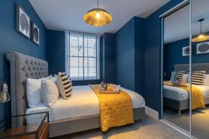 切尔滕纳姆Elliot Oliver - Luxury 2 Bedroom Regency Apartment With Parking & EV Charger的一间蓝色卧室,配有一张床和镜子