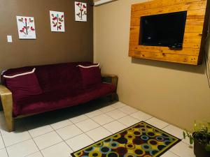 伯利兹城City Garden 2 Apartment的客厅配有红色沙发和平面电视