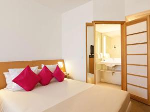 突尼斯诺富特突尼斯酒店的一间卧室配有一张带粉红色枕头和镜子的床