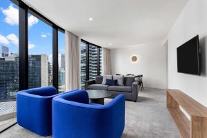 墨尔本Adina Apartment Hotel Melbourne Southbank的客厅配有蓝色椅子和电视