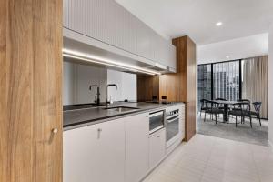 墨尔本Adina Apartment Hotel Melbourne Southbank的厨房配有白色橱柜、水槽和桌子