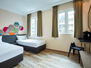 新加坡ibis budget Singapore Emerald的酒店客房,配有两张床和椅子
