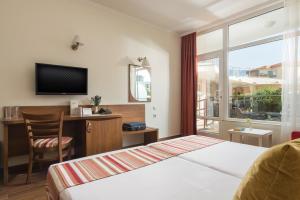 索佐波尔Hotel Miramar Sozopol的配有一张床、一张书桌和一扇窗户的酒店客房