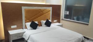 Pura RaghunāthHotel K J International的卧室配有一张带黑色枕头的大型白色床。