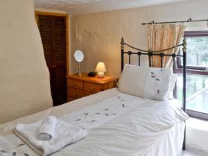 圣阿格尼丝班斯维尔度假屋的一间卧室配有一张带白色床单的床和一扇窗户。