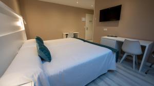 索托德尔瓦尔科Hotel El Parador的卧室配有白色的床、书桌和电视。